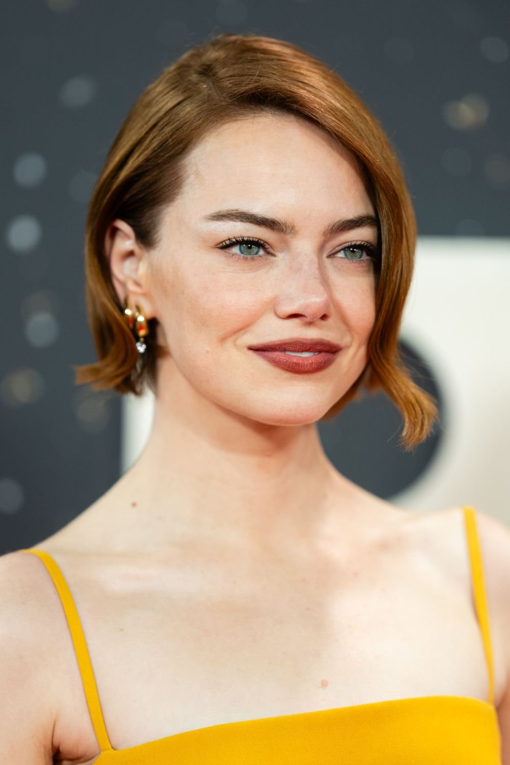 Emma Stone on the red carpet in a yellow dress with her hair worn with a deep side parting